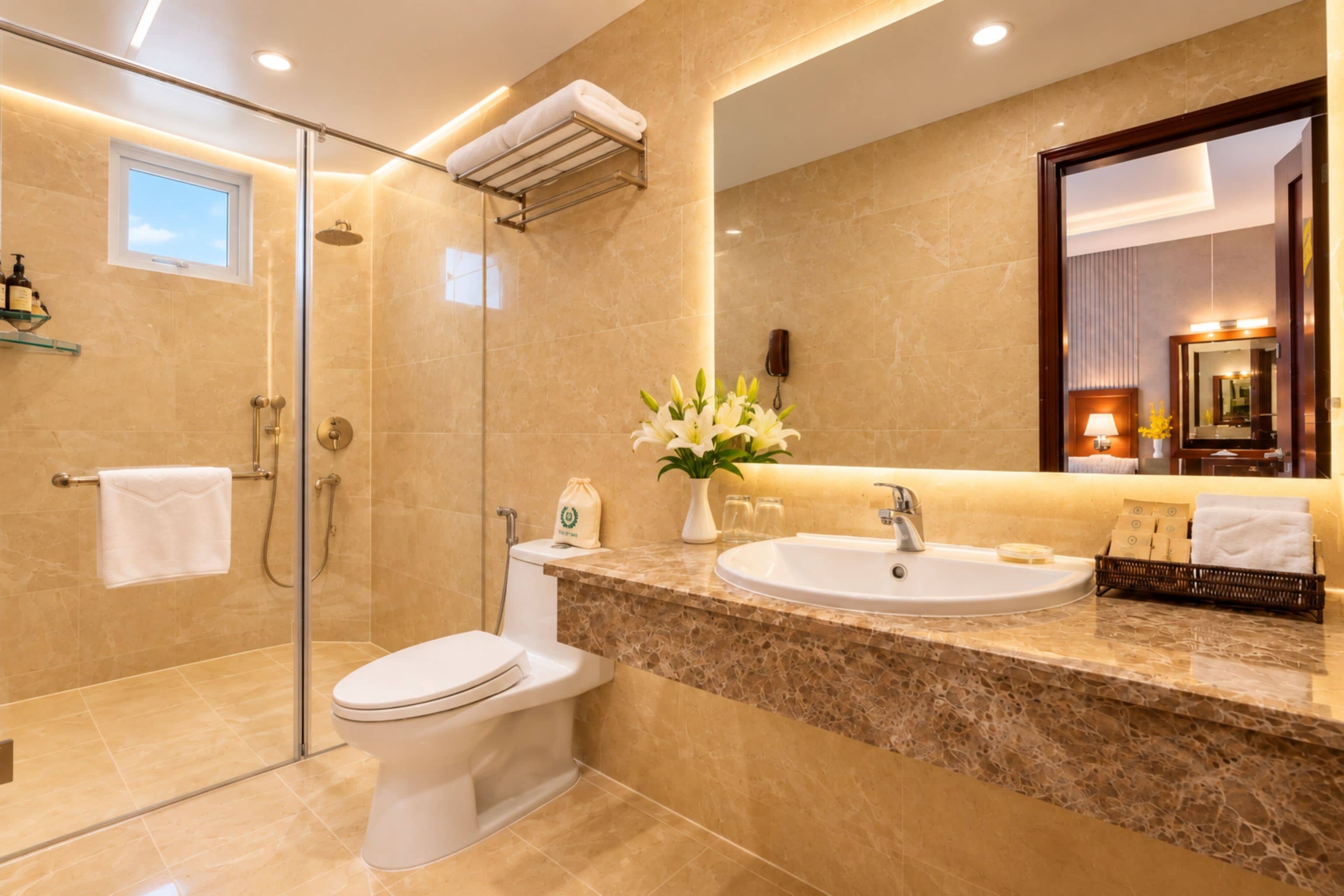 A modern bathroom with a glass shower enclosure, a toilet, a sink with a marble countertop, and a large mirror.