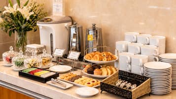 Un buffet proposant une variété de plats, des machines à café et des distributeurs de thé.