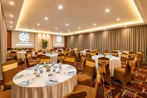 A conference room with multiple round tables, each with chairs and table settings, including water bottles and documents.