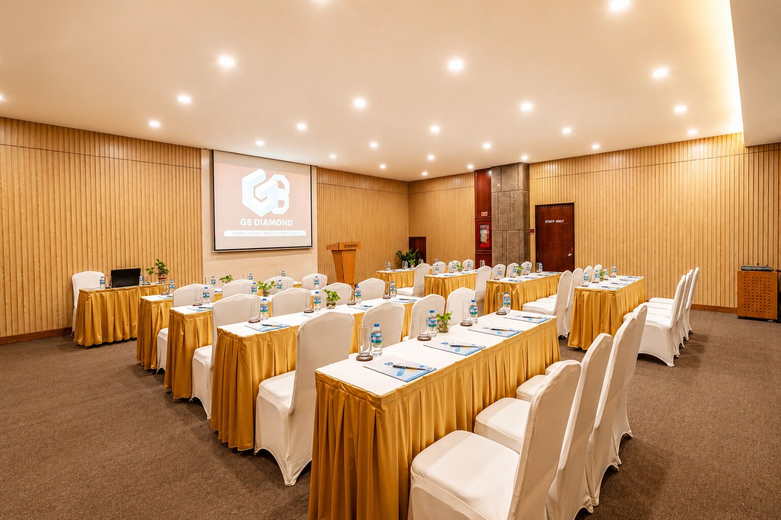 A conference room with multiple tables, chairs, and a presentation screen.