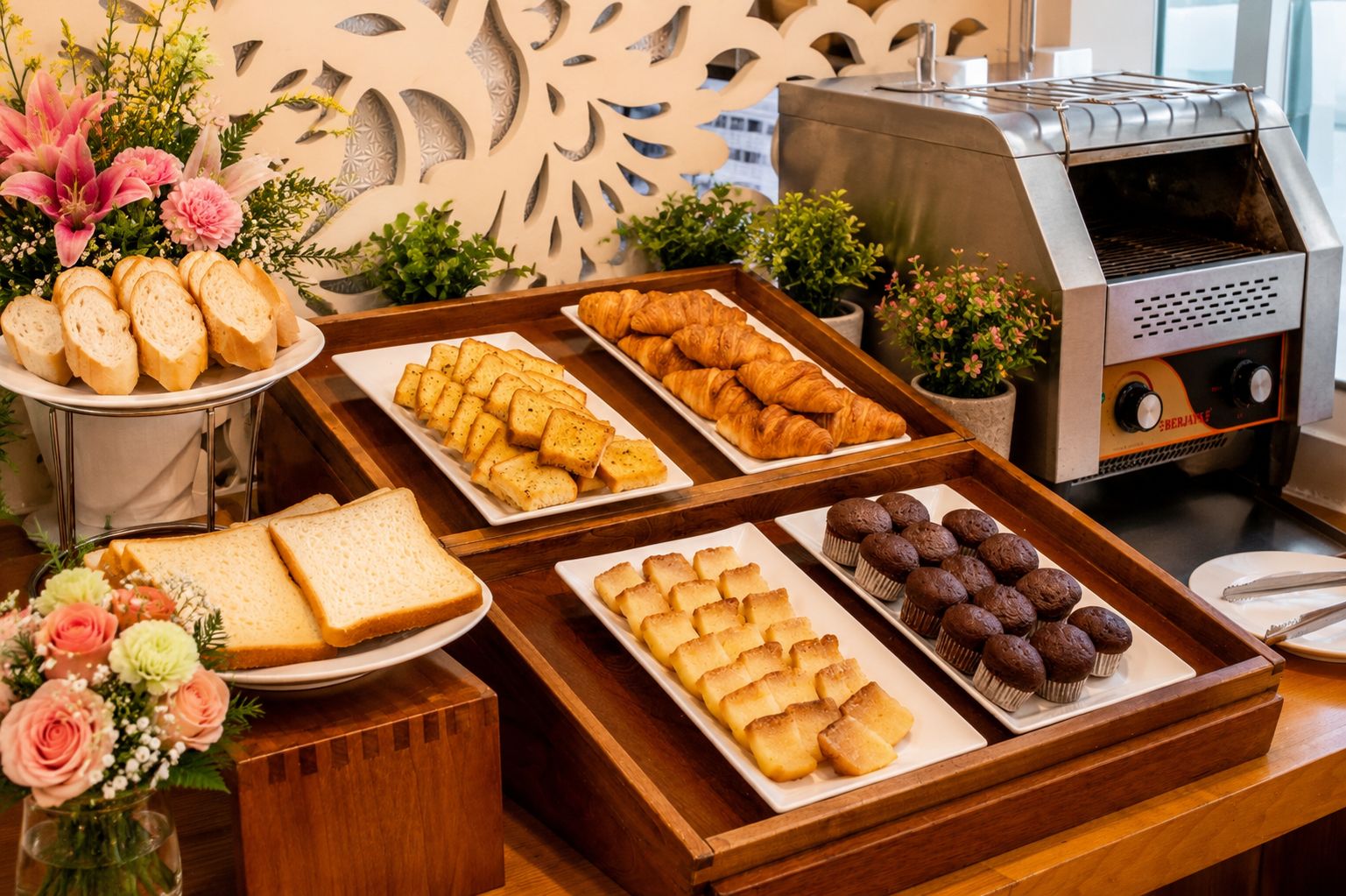 A buffet table with various food items including bread, croissants, muffins, and pastries.