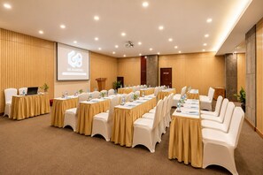 Un salón de conferencias con varias mesas y sillas, un atril y una pantalla mostrando 'G8 DIAMOND'.