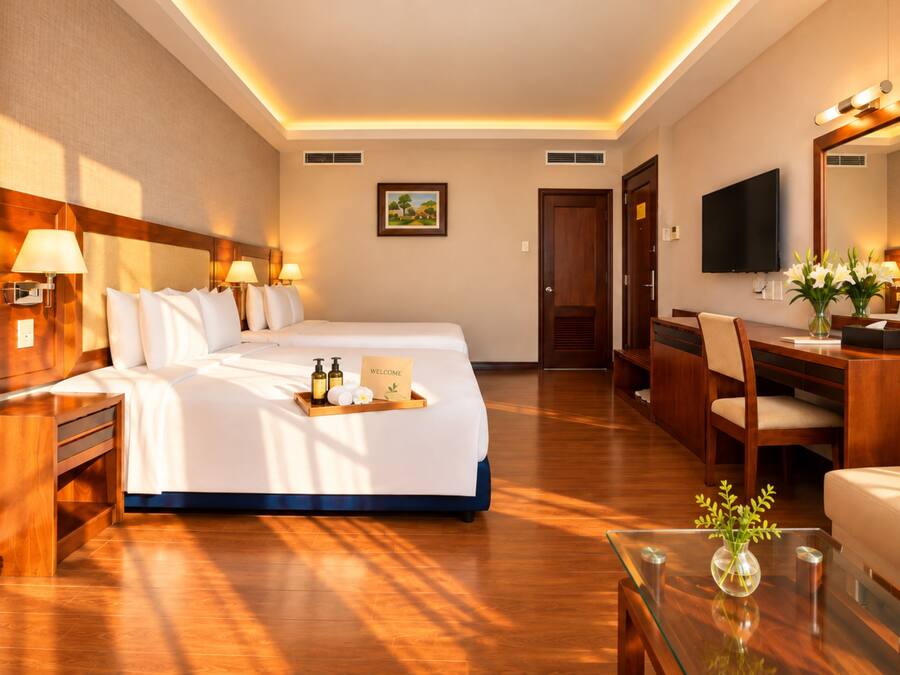 A hotel room with a large bed, bedside tables, a desk, a chair, a television, and a mirror.