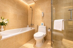 A modern bathroom with a bathtub, toilet, and glass shower enclosure.