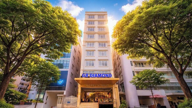 L’entrée d’un hôtel, avec une enseigne indiquant « G8 Diamond Hotel & Spa », entourée d’arbres.