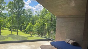 A room with a view of a green landscape, a blue sofa, and a small round table. - Equilibrium Villa Relais Plitvice (Rakovica)