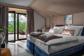 A bedroom with a large bed, a chair, a desk, and a view through a glass door. - Equilibrium Villa Relais Plitvice (Rakovica)