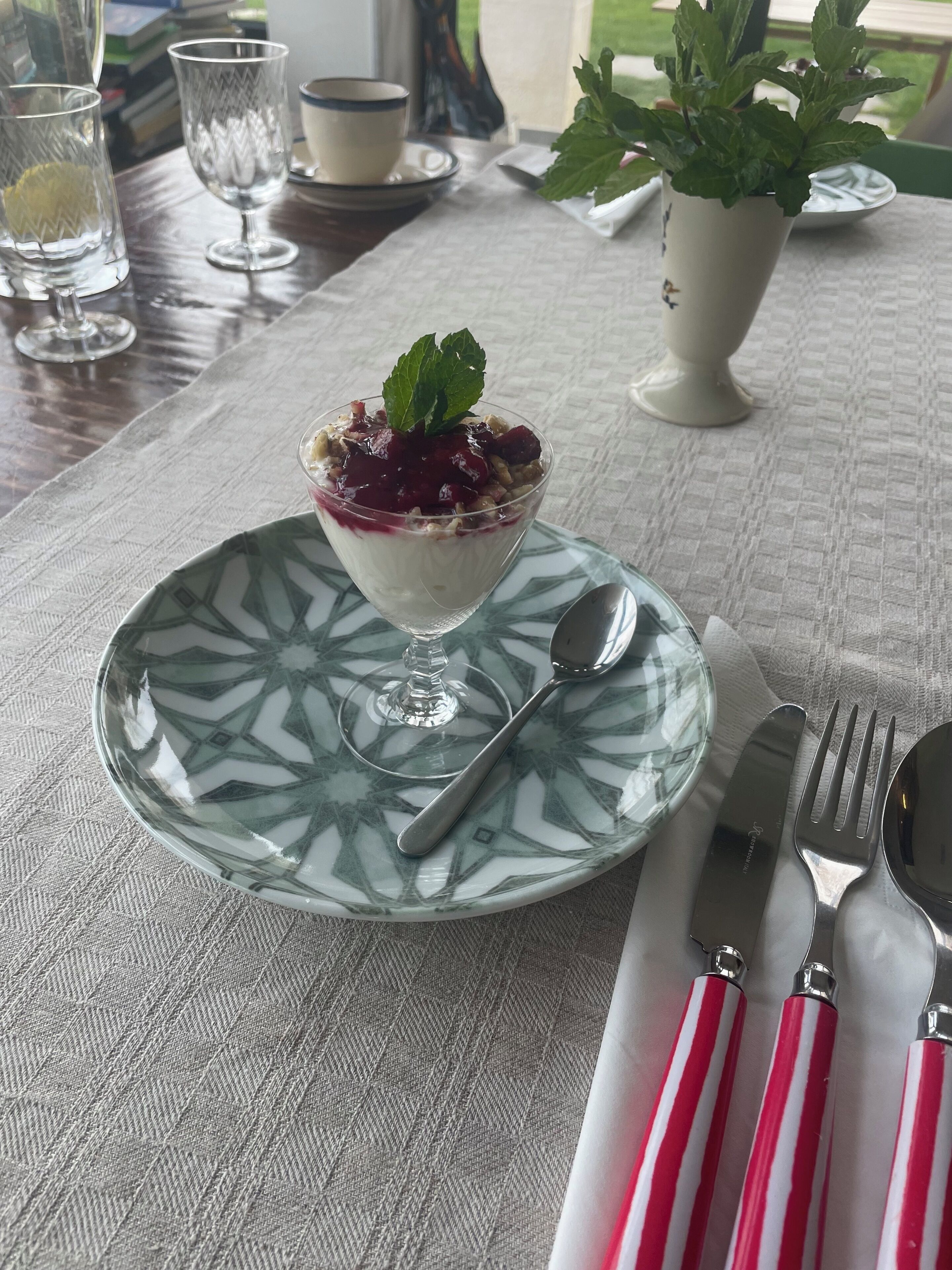 Een dessert op een bord met patroon, met een lepel en bestek op een tafelkleed.