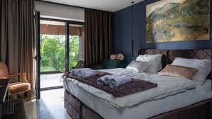 A bedroom with a bed, a painting, a view through the window, and a chair. - Equilibrium Villa Relais Plitvice (Rakovica)