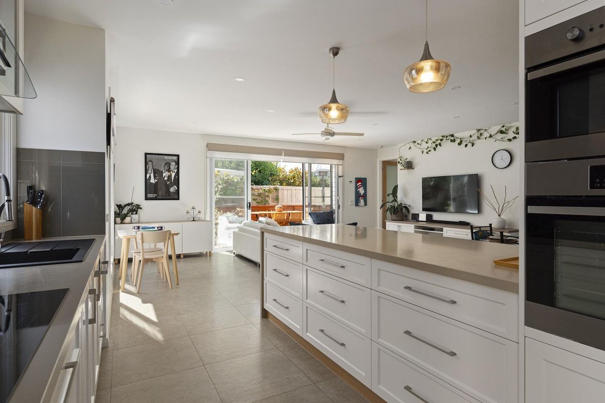 A modern kitchen with a large island, stainless steel appliances, and a dining area with natural light.