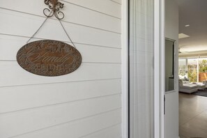 Ein Metallschild mit der Aufschrift 'Welcome Family Friends' an einer weißen Holzwand.