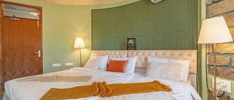 Une chambre d’hôtel avec un lit, une porte en bois, un climatiseur et une lampe.