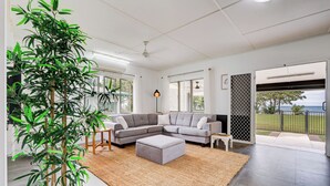 Un salon moderne avec un canapé d’angle, une table basse et une grande plante en pot.