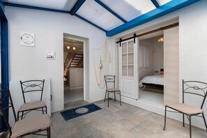 A room with a skylight, a bed, a chair, and a door leading to another room.