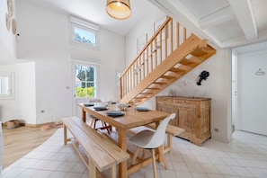A dining area with a wooden table, benches, and a staircase.