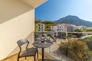A balcony with a table, two chairs, a bottle of wine, and two wine glasses. - Altiora Prestige Residence 205 (Gradac)