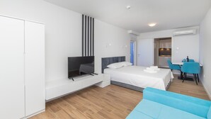 Une chambre d’hôtel moderne équipée d’un lit, d’une télévision, d’un bureau et d’un canapé bleu.