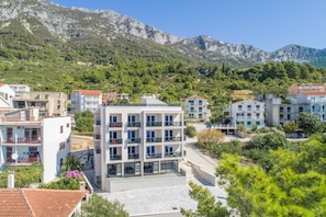 A modern building with multiple balconies, surrounded by greenery and mountains. - Altiora Prestige Residence 201 (Gradac)