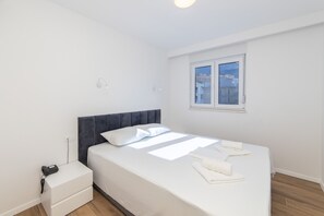 Ein Schlafzimmer mit einem Bett, einem Nachttisch, einem Fenster und einer Steckdose.