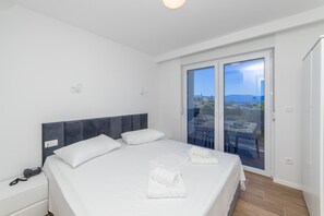 A modern hotel room with a large bed, a bedside telephone, and a balcony with a city view. - Altiora Prestige Residence 302 (Gradac)