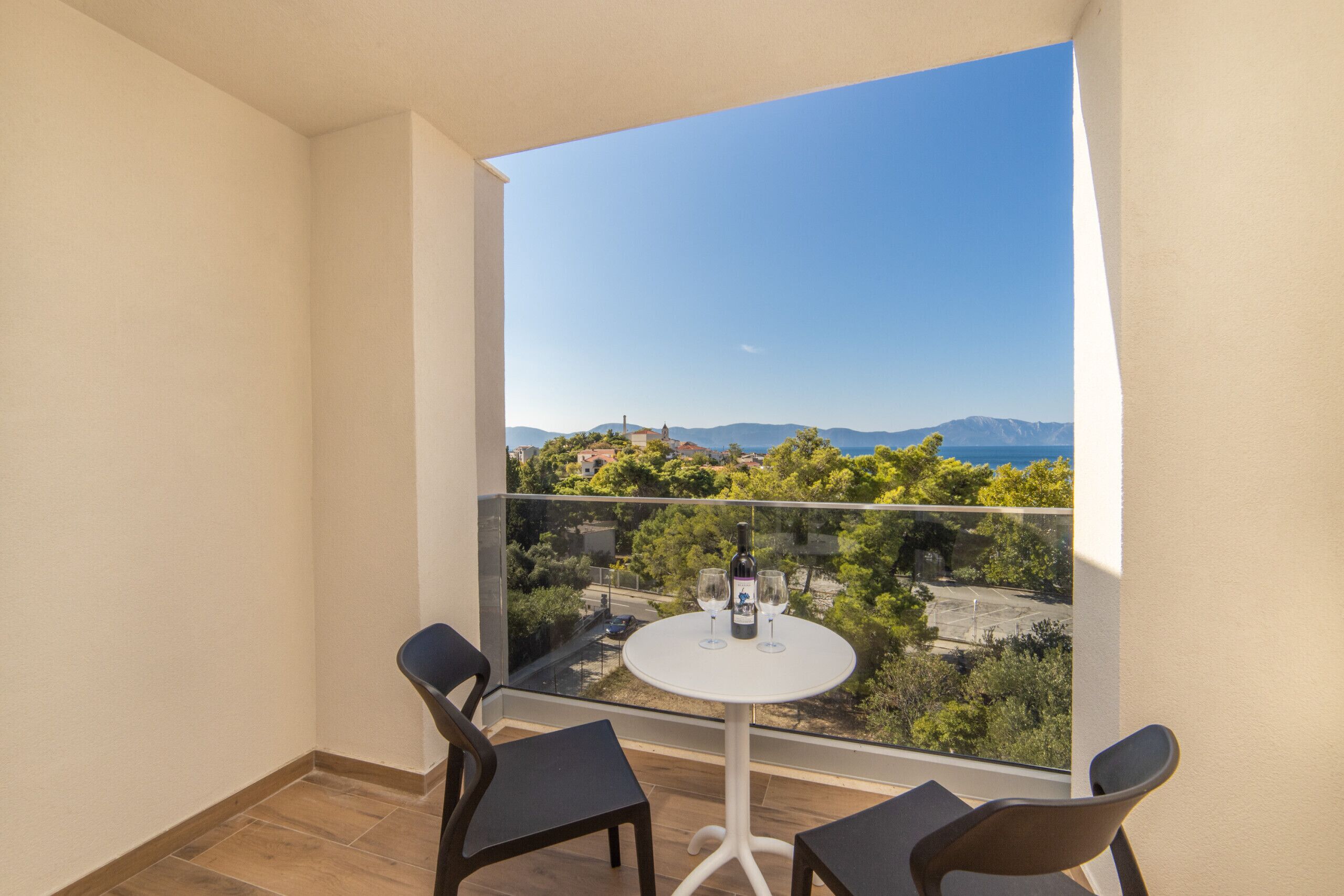 A balcony with two chairs and a table, a bottle, and two glasses.