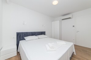 A clean, modern hotel room with a neatly made bed, a wardrobe, and an air conditioning unit. - Altiora Prestige Residence 104 (Gradac)