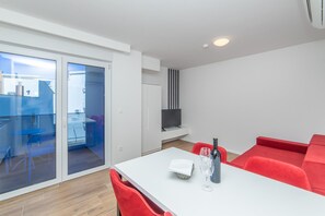 Ein modernes Zimmer mit einem weißen Tisch, roten Stühlen, einer Glastrennwand und einem roten Sofa.