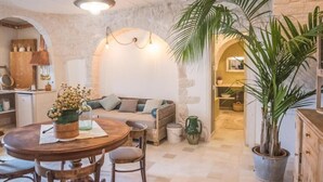 A cozy living area with a round wooden table, a sofa, and a large potted plant. - Navolte Trulli e Piscina (Locorotondo)