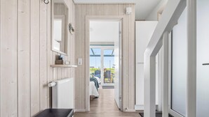 Ein Flur mit Holzwänden, einem Heizkörper, einer Sitzbank und Blick auf einen Balkon mit Gartenmöbeln.