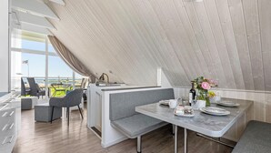 Eine moderne Küche mit Essbereich, großen Fenstern und Meerblick.