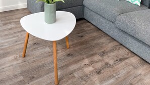 Una sala de estar moderna con un sofá gris, una mesa de centro blanca y un cuadro de un barco en la pared.