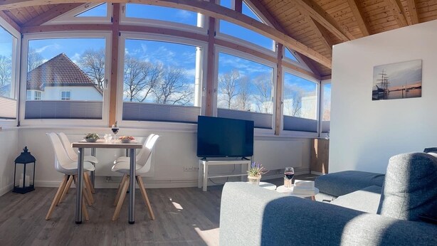 Una habitación con una mesa de comedor, sillas, un televisor y un sofá.