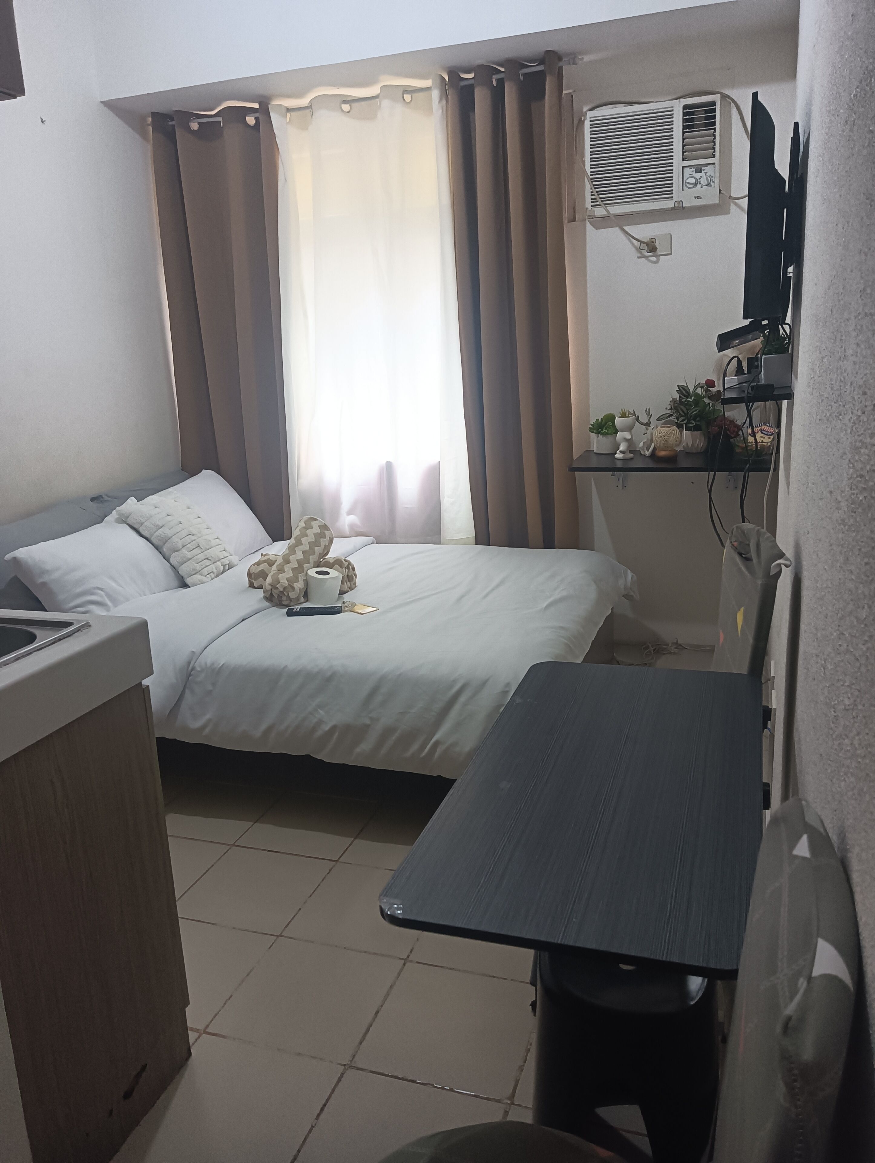 A compact hotel room with a bed, bedside table, and a small desk area.