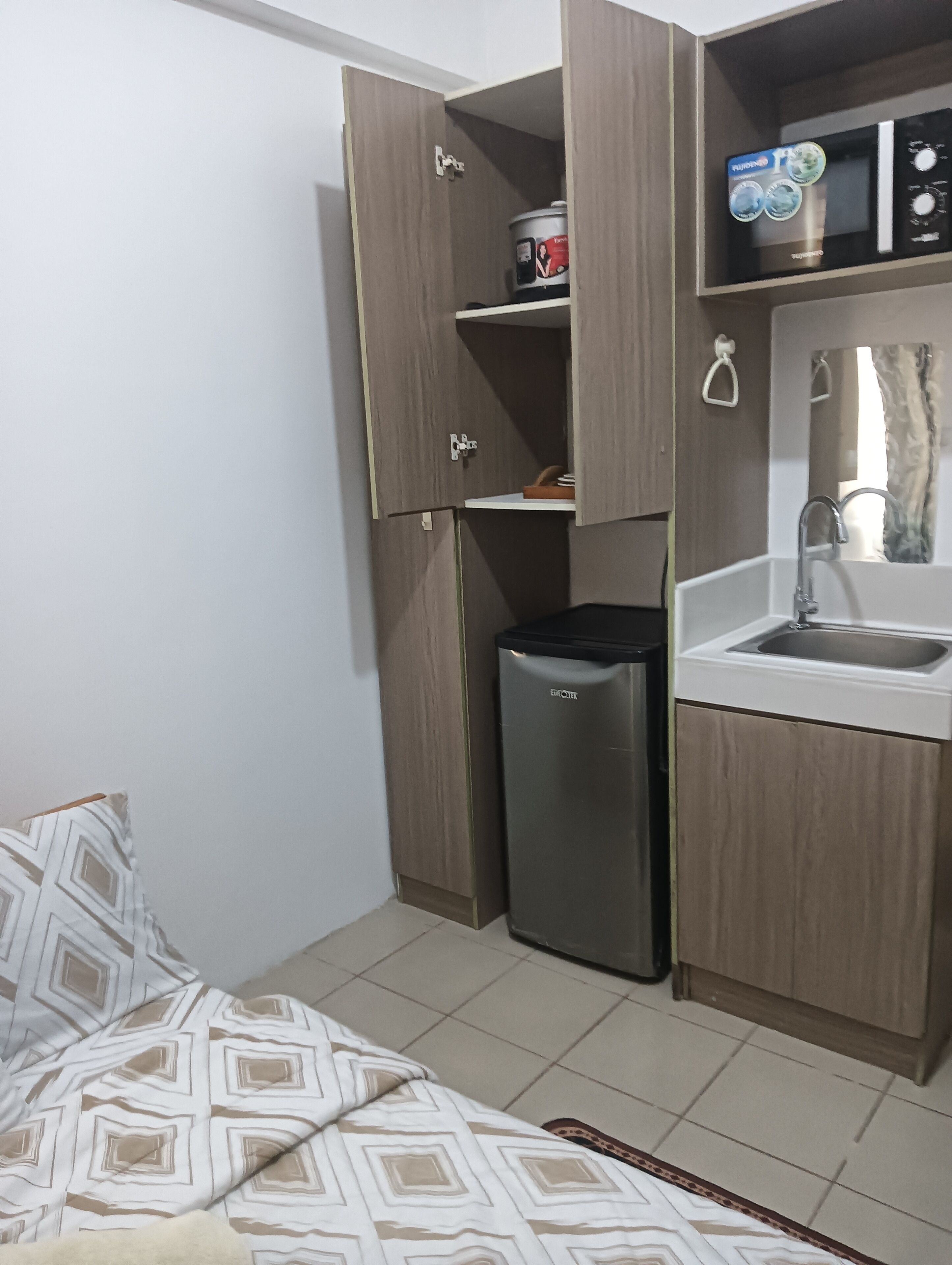 A compact kitchen with a sink, a microwave, and a small trash bin.