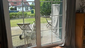 Ein Zimmer mit einer großen Schiebetür, die auf eine Terrasse mit Holzstuhl und Tisch führt.