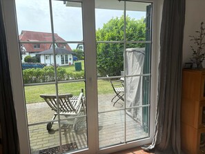 Ein Zimmer mit einer großen Schiebetür, die auf eine Terrasse mit Holzstuhl und Tisch führt.