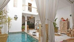 A pool area with a clear view of the pool, a chair, and a cabinet. - Riad Larbi Khalis Room Essaouira (Marrakesh)