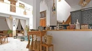 A spacious living area with a high ceiling, a kitchen with decorative items, and a view of the outdoors. - Riad Larbi Khalis Room Essaouira (Marrakesh)