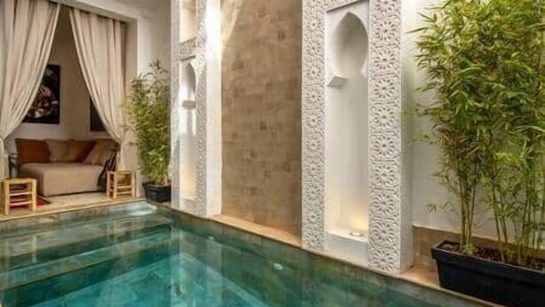 A swimming pool with a sofa and potted plants in a room with decorative walls. - Riad Larbi Khalis Room Essaouira (Marrakesh)
