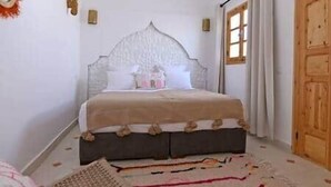 A bedroom with a bed, a wooden door, and a window. - Riad Larbi Khalis Room Essaouira (Marrakesh)