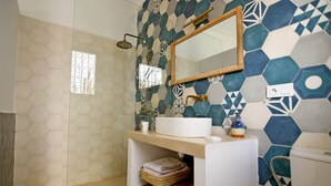 A bathroom with a hexagonal tile pattern, a white sink, a mirror, and a shower area. - Riad Larbi Khalis Room Taghazout (Marrakesh)