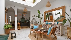 Un amplio espacio interior con piscina, un comedor y una cocina visible al fondo.