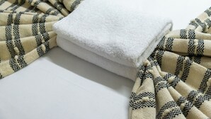 Ein weißes Handtuch und ein gemustertes Gewebe auf einer flachen Oberfläche.