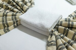 Ein weißes Handtuch und ein gemustertes Gewebe auf einer flachen Oberfläche.