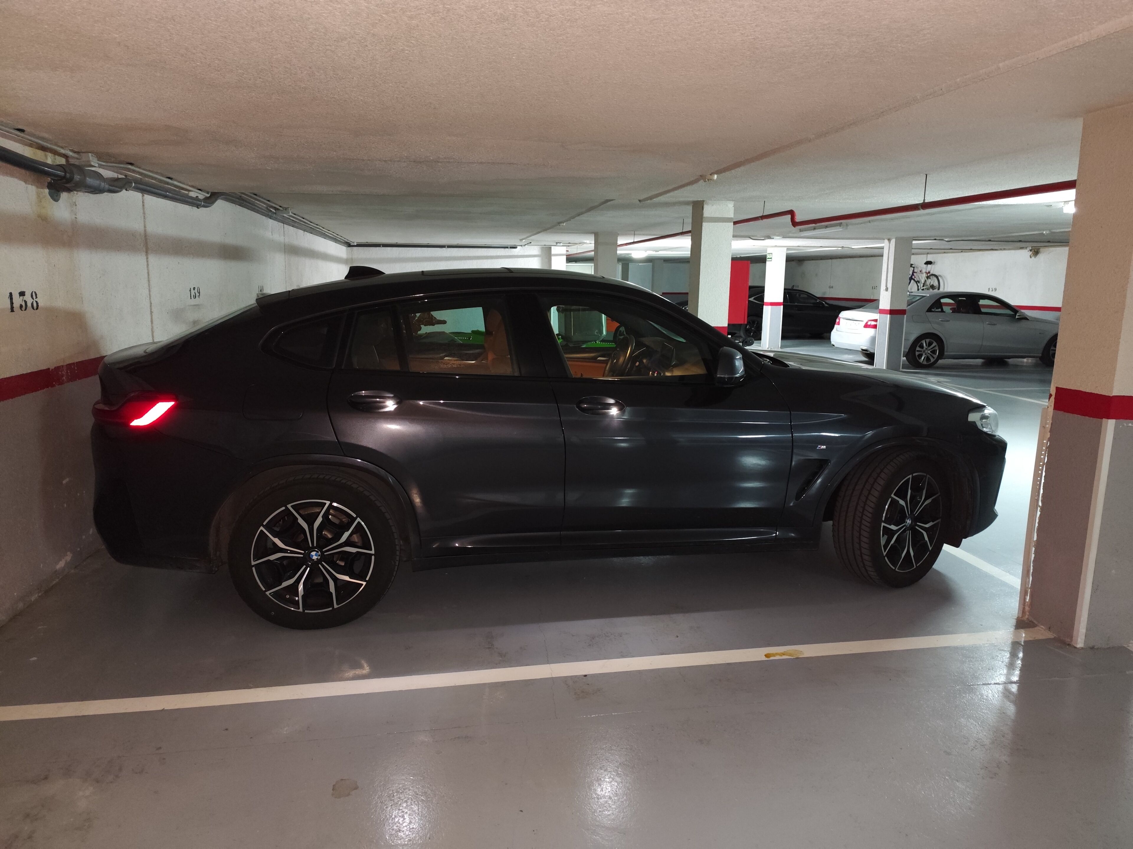 A parking garage with a black car parked in a spot marked 159.