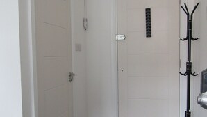 A room with a closed door, a coat rack, and a table with a chair. - Cozy Studio Rental With Private Facilities in Greater London (Welling)