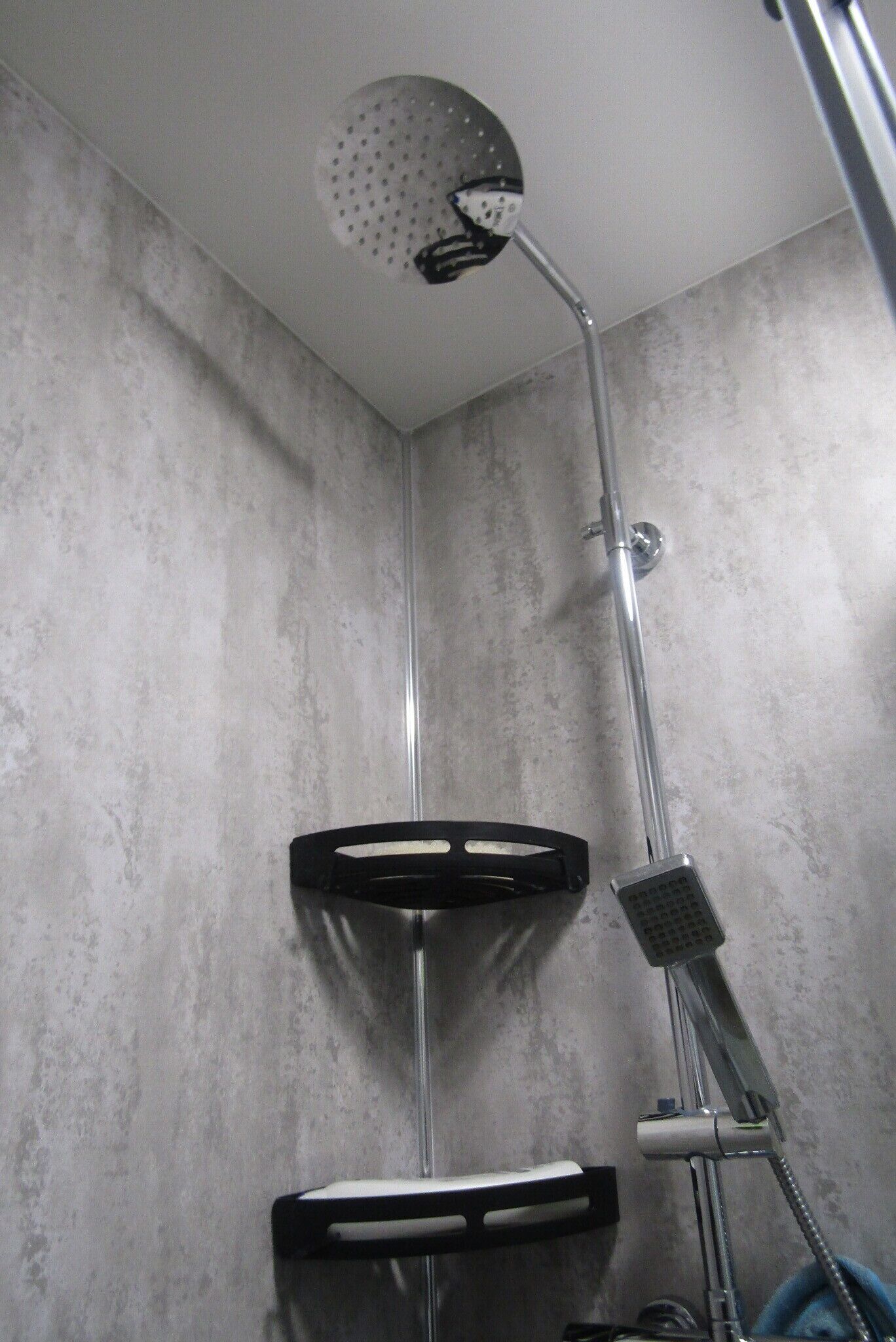 Ducha con cabezal de ducha de mano, grifo empotrado en la pared y dispensador de jabón.