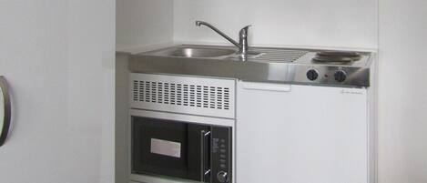 Une cuisine compacte équipée d’un évier, d’une cuisinière et d’un four à micro-ondes.