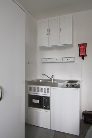 A compact kitchen with a sink, stove, and microwave. - Cozy Studio Rental With Private Facilities in Greater London (Welling)