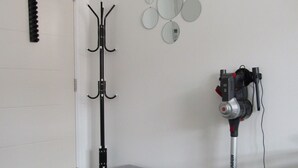 A room with a coat rack, a vacuum cleaner, a bench, and a door. - Cozy Studio Rental With Private Facilities in Greater London (Welling)